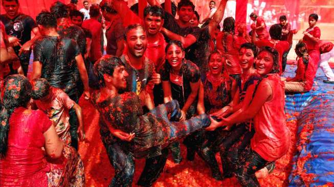 Sekelompok anak muda asyik bermain dengan bubur tomat, sebagai bagian dari perayaan Holi, di Ahmedabad, kota sebelah barat India, Jumat (6/3/2015). [Reuters/Amit Dave]