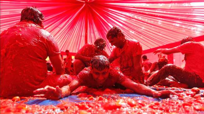 Sekelompok anak muda asyik bermain dengan bubur tomat, sebagai bagian dari perayaan Holi, di Ahmedabad, kota sebelah barat India, Jumat (6/3/2015). [Reuters/Amit Dave]