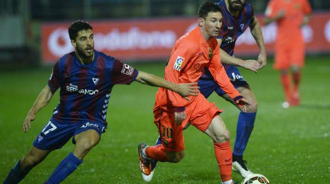 Pemain Barcelona Lionel Messi (tengah) membawa bola coba dihalangi dua pemain Eibar (15/3).  REUTERS/Vincent West