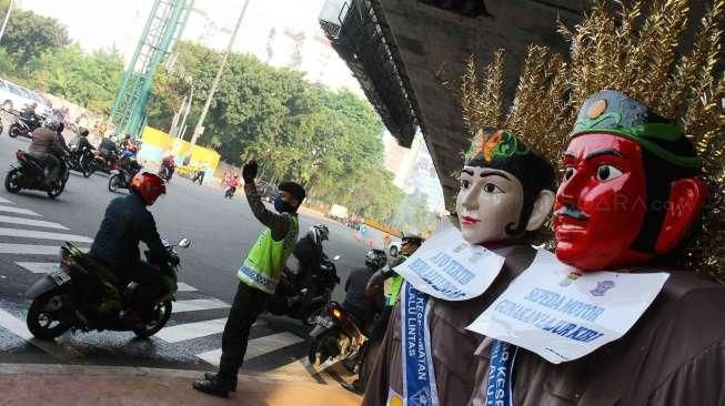 Polisi Lalu Lintas dibantu ondel-ondel mengatur lalu lintas di Flyover Kuningan, Jakarta Selatan, Kamis (19/3).