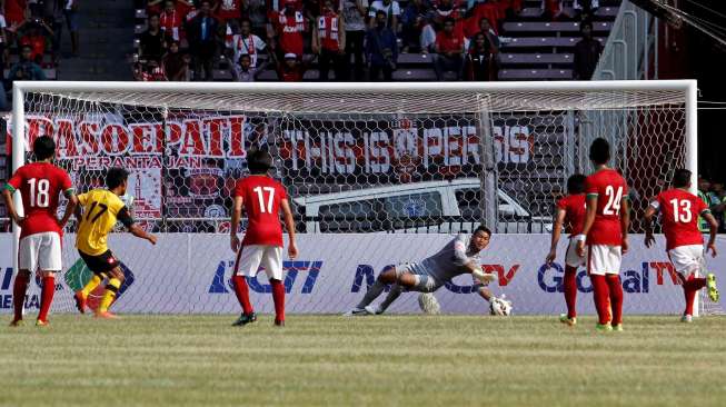 Kiper Tim Indonesia U-23 M Natsir saat menepis tendangan penalti pemain Brunei Darussalam Mohammad Aimil. [suara.com/Kurniawan Mas'ud]