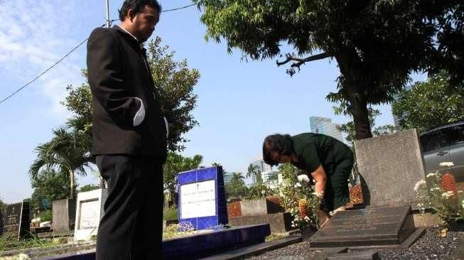 Sejumlah umat Kristiani tampak berdoa sembari membersihkan makam keluarga dan kerabatnya di beberapa TPU di Jakarta, pada momen Paskah, Minggu (5/4/2015). [Suara.com/Oke Atmaja]