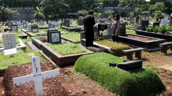 Sejumlah umat Kristiani tampak berdoa sembari membersihkan makam keluarga dan kerabatnya di beberapa TPU di Jakarta, pada momen Paskah, Minggu (5/4/2015). [Suara.com/Oke Atmaja]