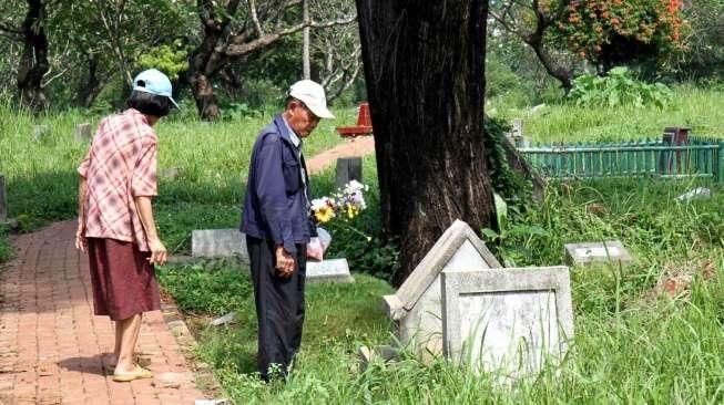 Sejumlah umat Kristiani tampak berdoa sembari membersihkan makam keluarga dan kerabatnya di beberapa TPU di Jakarta, pada momen Paskah, Minggu (5/4/2015). [Suara.com/Oke Atmaja]