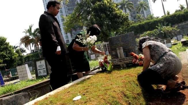 Sejumlah umat Kristiani tampak berdoa sembari membersihkan makam keluarga dan kerabatnya di beberapa TPU di Jakarta, pada momen Paskah, Minggu (5/4/2015). [Suara.com/Oke Atmaja]