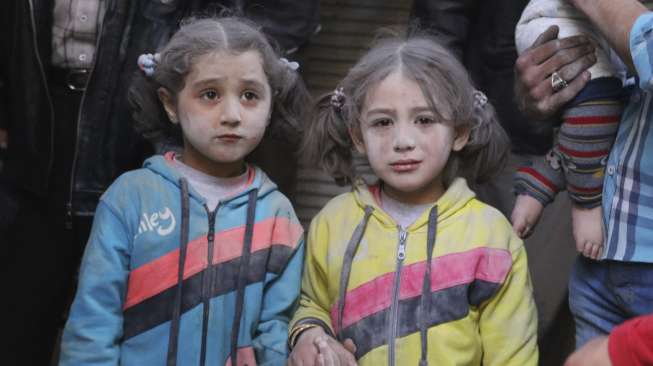 Dua gadis kecil yang selamat dari serangan rudal di Distrik Bab al-Hadeed, Kota Aleppo, Suriah, luluh lantak oleh ledakan, (7/4). Aktivis setempat mengklaim ledakan berasal dari rudal darat ke darat. [Reuters/Abdalrahman Ismail]