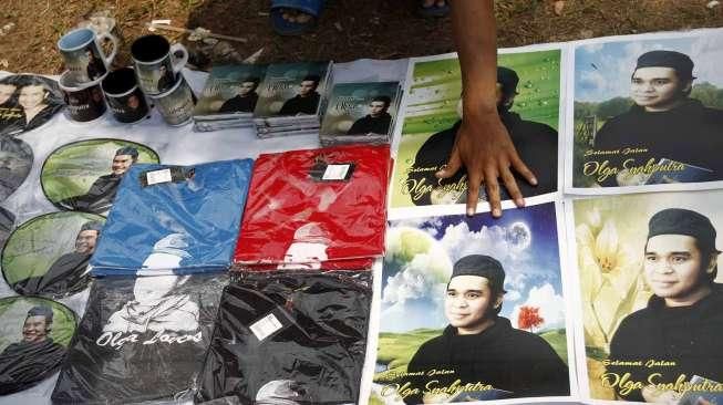 Pedagang berjualan cenderamata seperti mug, buku Surat Yasin, kalender, gantungan kunci, kaos dan pernak-pernik lain bergambar Olga Syahputra di TPU Malaka Duren Sawit Jakarta Timur, Jumat (10/4).[Suara.com/Kurniawan Mas'ud]