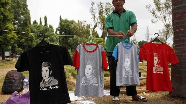 Pedagang berjualan cenderamata seperti mug, buku Surat Yasin, kalender, gantungan kunci, kaos dan pernak-pernik lain bergambar Olga Syahputra di TPU Malaka Duren Sawit Jakarta Timur, Jumat (10/4).[Suara.com/Kurniawan Mas'ud]