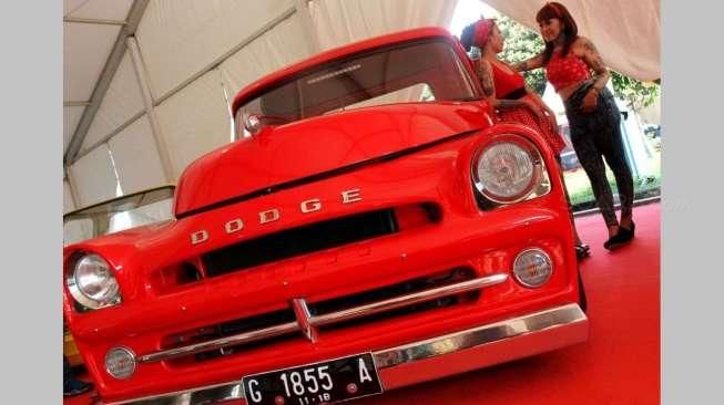 Beberapa orang perempuan bertato berpose di antara jejeran mobil-mobil klasik hot rod yang dipajang di lokasi acara Indonesia Greaser Party 2015, Jumat (10/4/2015), di Plaza Barat Senayan. [Suara.com/Oke Atmaja]