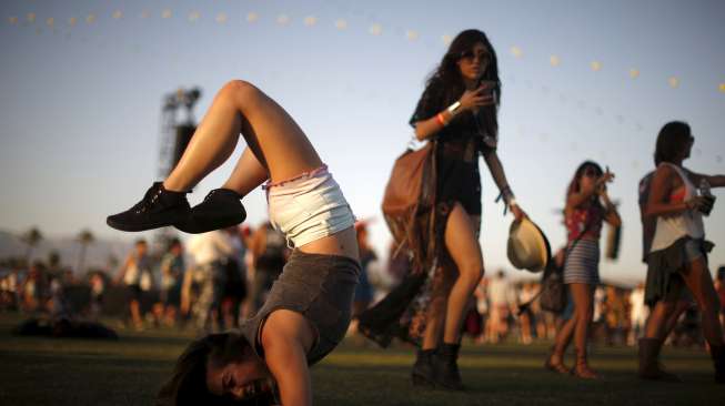 Seorang perempuan berakrobat sembari menunggu pertunjukan band di Coachella Valley Music and Arts Festival, (12/4). [Reuters/Lucy Nicholson]