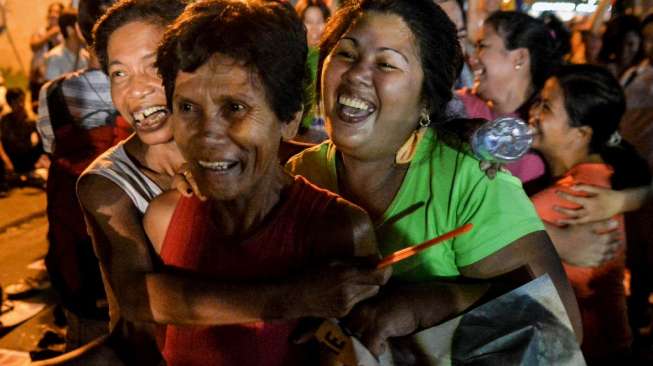 Aktivis Filipina berteriak kegirangan, berjingkrak dan berpelukan mengetahui penundaan eksekusi terhadap Mary Jane, hari Rabu (29/4/2015) dini hari di depan Kedubes Indonesia di Makati, Filipina. [Reuters/Ezra Acayan]