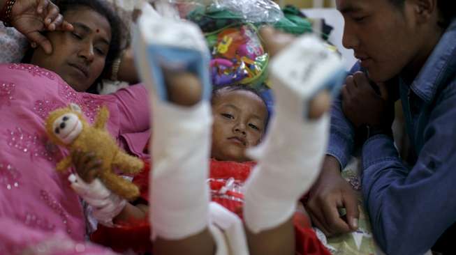 Jenisha Nagarkati (2), salah seorang bocah korban selamat gempa Nepal, berbaring bersama ibu dan ayahnya, di ranjang rumah sakit di Pokkara, Nepal, Kamis (30/4/2015). [Reuters/Athit Perawongmetha]