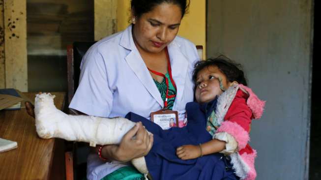 Seorang bidan menggendong bocah 4 tahun korba gempa Nepal, bernama Ritu Rana, saat dia hendak menjalani pemeriksaan x-ray untuk kakinya yang patah, Kamis (30/4/2015), di Gorkha, Nepal. [Reuters/Wolfgang Rattay]