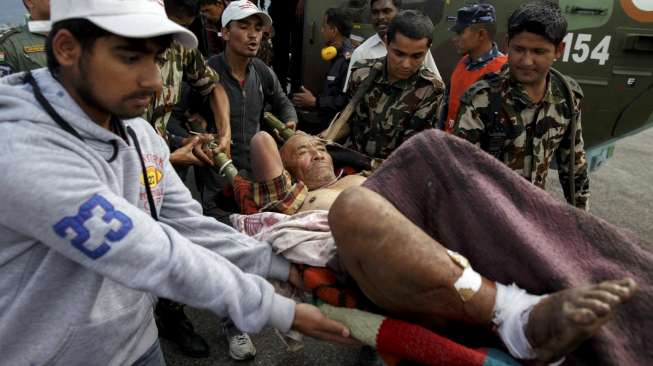 Personel militer Nepal dan sukarelawan lainnya menggotong salah satu korban gempa Nepal, Buddha Gurung, setelah dibawa dari desanya ke Bandara Pokkara, Nepal, Kamis (30/4/2015). [Reuters/Athit Perawongmetha]