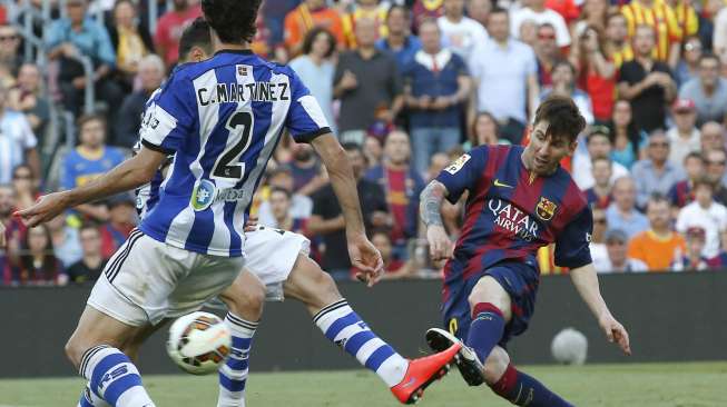 Pemain Barcelona Lionel Messi melepaskan tendangan dan coba dihalangi oleh dua pemain Real Sociedad di Camp Nou. Reuters/Gustau Nacarino