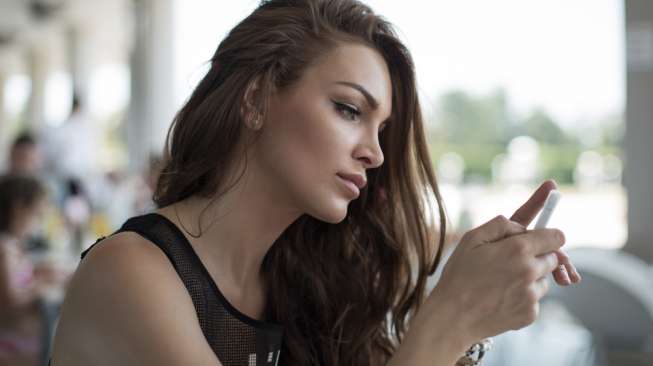 Ilustrasi perempuan memakai telepon genggam. (Shutterstock)