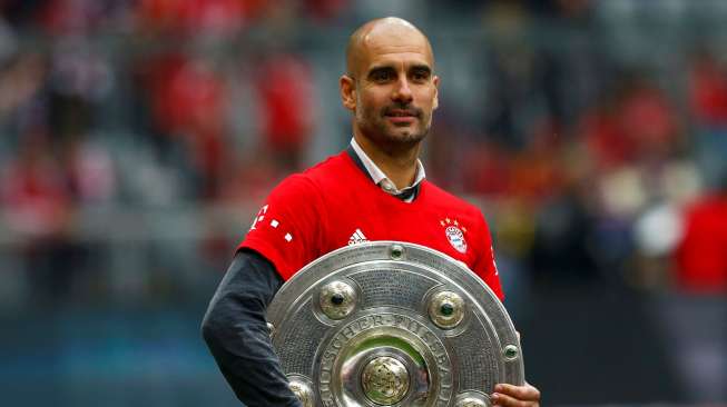 Pelatih Bayern Munich Pep Guardiola memegang trofi Bundesliga. Reuters/Michael Dalder