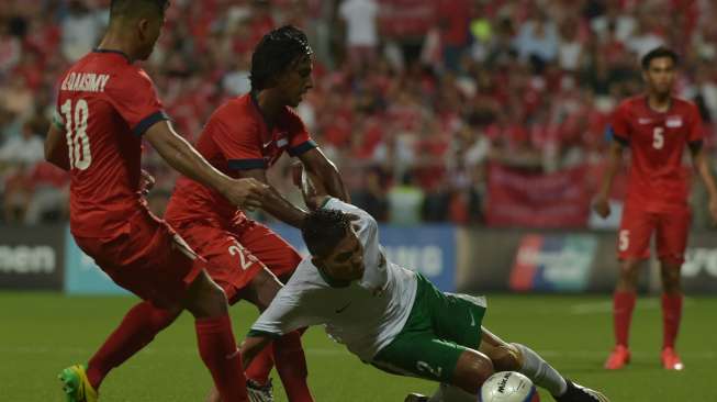 Mario Yagalo Vava (kanan) berebut bola dengan pemain Singapura, Suria Prakash S (tengah) dan Muhammad Al-Qaasimy Abdul Rahman dalam pertandingan Sepak Bola Sea Games ke-28 di Stadion Jalan Besar, Singapura(11/6). [Antara]