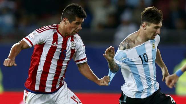 Pemain Paraguay susah payah hentikan laju Messi (14/6) [Reuters/Marcos Brindicci]