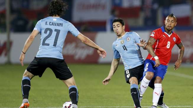 Pemain Uruguay Jorge Fucile menjatuhkan pemain Cile Arturo Vidal (25/6) [Reuters/Ueslei Marcelino]