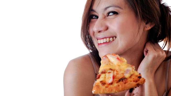 Ilustrasi perempuan makan pizza. (Shutterstock)