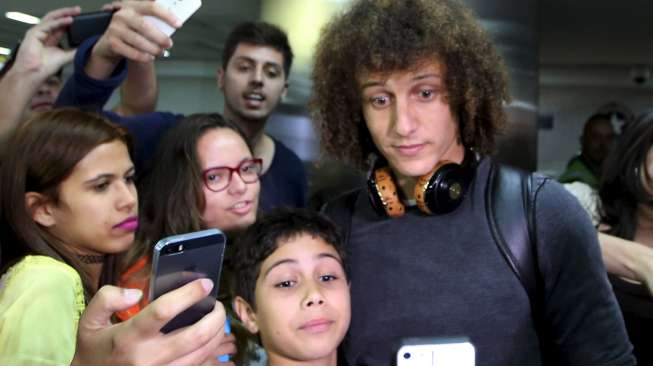 Pemain Brasil David Luiz meladeni permintaan para fansnya yang ingin selfie saat  tiba di Bandara internasional Guarulhos, Sao Paolo (28/6). Reuters/Paulo Whitaker