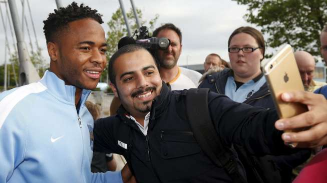 Pemain baru Manchester City Raheem Sterling menerima ajakan berfoto fansnya di di Etihad Stadium.  Reuters/Andrew Yates