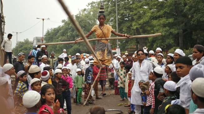 Seorang jago akrobat melakukan atraksi keseimbangannya di atas tali, di tengah perayaan Idul Fitri di New Delhi, India, Sabtu (18/7/2015). [Reuters/Anindito Mukherjee]