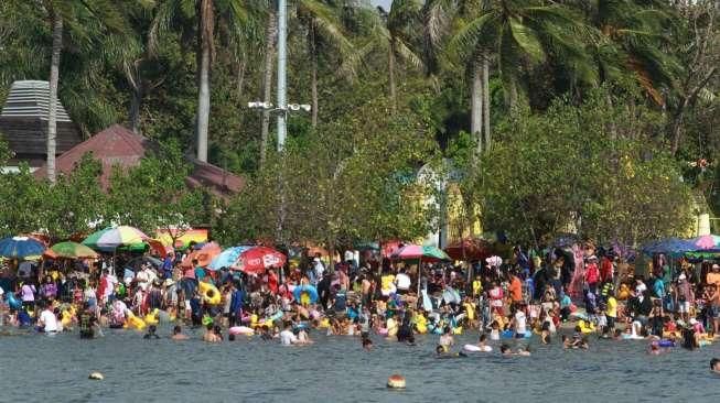 Pengunjung tampak berenang dan menikmati aktivitas liburan di Pantai Ancol, Jakarta, Minggu (19/7/2015). [Suara.com/Oke Atmaja]