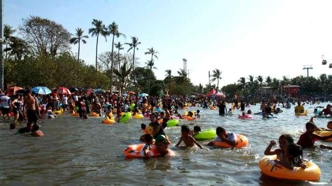 Pengunjung tampak berenang dan menikmati aktivitas liburan di Pantai Ancol, Jakarta, Minggu (19/7/2015). [Suara.com/Oke Atmaja]