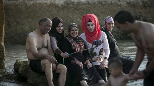 Masyarakat Palestina yang bermukim di Tepi Barat memadati pantai pesisir Laut Mediterania, (19/7), bertepatan dengan hari ketiga perayaan Hari Raya Idul Fitri 1436H. [Reuters/Baz Ratner]