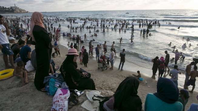 Masyarakat Palestina yang bermukim di Tepi Barat memadati pantai pesisir Laut Mediterania, (19/7), bertepatan dengan hari ketiga perayaan Hari Raya Idul Fitri 1436H. [Reuters/Baz Ratner]