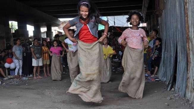 Masyarakat, termasuk anak-anak, mengikuti perayaan HUT Kemerdekaan Republik Indonesia yang ke-70 Tahun di kawasan kolong jembatan layang Lodan, Kampung Bandan, Jakarta, Senin (17/8). [Suara.com/Kurniawan Mas'ud]