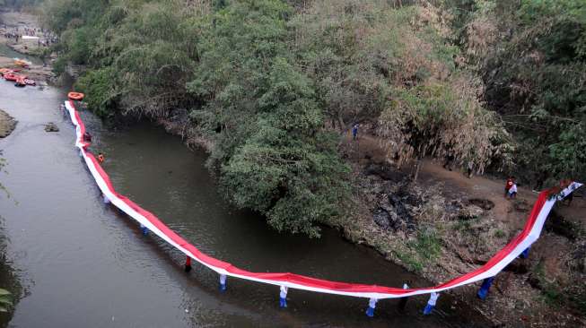 Sejumlah pelajar bersama Komunitas Ciliwung Depok membentangkan bendera Merah Putih sepanjang 70 meter, saat menyusuri Sungai Ciliwung, Depok, Jawa Barat, Senin (17/8/2015). [Antara/Indrianto Eko Suwarso]