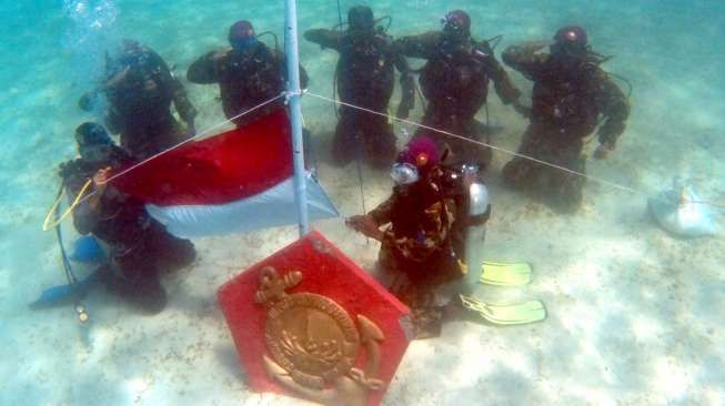 Prajurit Batalyon Marinir Pertahanan Pangkalan VI Makassar bersama personel SAT Polair, mengibarkan bendera Merah Putih di dasar laut Pulau Samalona, Makassar, Sulsel, Minggu (16/8/2015). [Antara/Dewi Fajriani]