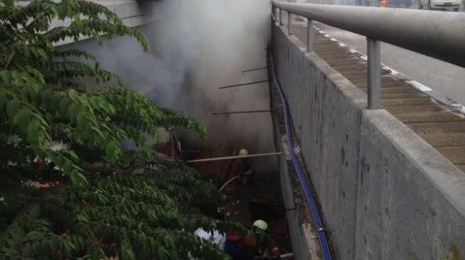 Petugas memadamkan api yang melalap permukiman liar di bawah jembatan layang Kuningan, Jakarta, Rabu (19/8). [Suara.com/Kurniawan Mas'ud]