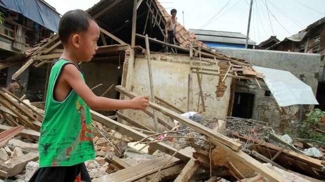 Sejumlah warga Kampung Pulo mencari harta bendanya yang tersisa, di puing-puing bangunan rumahnya yang dibongkar aparat di Jakarta, Kamis (20/8/2015). [Suara.com/Oke Atmaja]