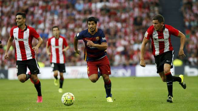 Striker Barcelona Luis Suarez (tengah) membawa bola ditempel pemain Athletic Bilbao. Reuters/Joseba Etxaburu
