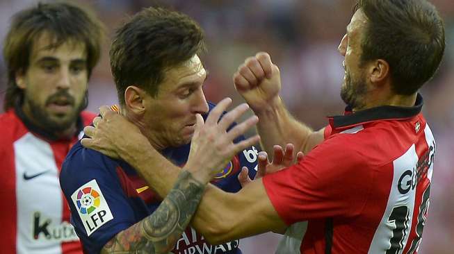 Pemain Barcelona Lionel Messi bentrok dengan pemain Athletic Bilbao Carlos Gurpegi. Reuters/Vincent West