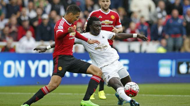 Pemain MU Chris Smalling mencoba menghentikan laju pemain Swansea Bafetimbi Gomis (30/8) [Reuters/John Sibley]