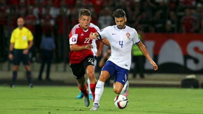 Pemain Albania Amir Abrashi (kiri) mencoba merebut bola dari pemain Portugal Miguel Veloso. Reuters/Arben Celi