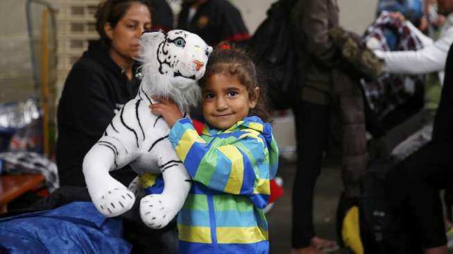 Seorang anak pengungsi memeluk boneka saat orangtuanya mendaftarkan diri sebagai pengungsi korban perang di Munich, Jerman [Reuters/Michael Dalder]
