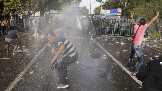 Pengungsi terlibat bentrok dengan polisi anti huru-hara Hungaria saat mencoba menyeberangi perbatasan negara tersebut dengan Serbia. [Reuters]