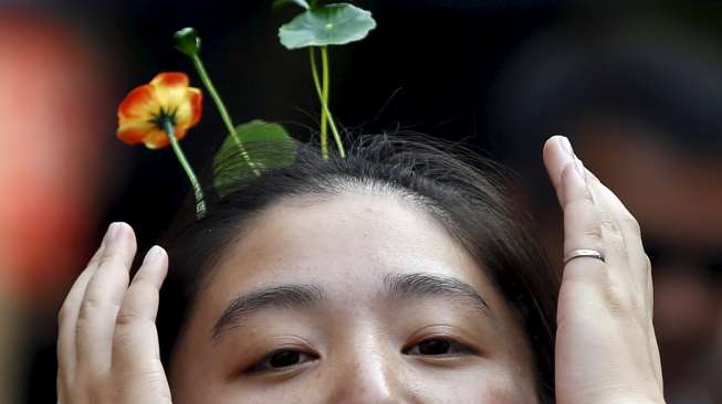 Warga Beijing, baik tua maupun muda mengenakan hiasan rambut berbentuk bunga dan tunas tanaman di jalan Nanluoguxiang, Beijing. [Reuters/Kim Kyung-Hoon]