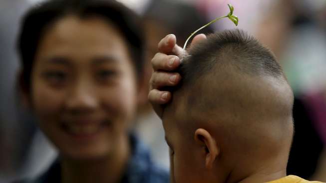 Warga Beijing, baik tua maupun muda mengenakan hiasan rambut berbentuk bunga dan tunas tanaman di jalan Nanluoguxiang, Beijing. [Reuters/Kim Kyung-Hoon]