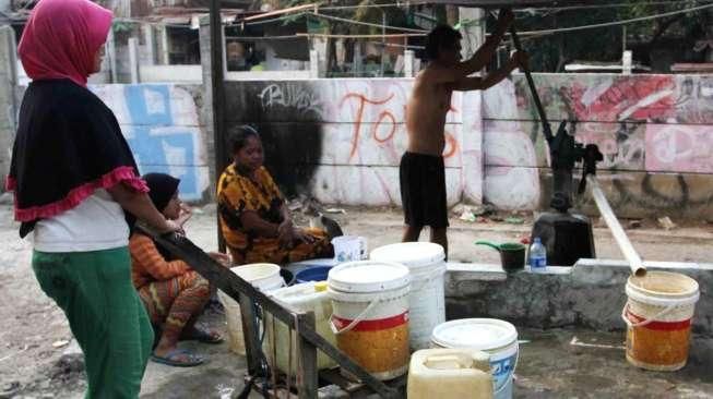 Sejumlah warga tampak bergiliran memompa air di sebuah pompa manual yang ada di Kelurahan Kebon Melati, Tanah Abang, Jakarta, Sabtu (26/9/2015). [Suara.com/Oke Atmaja]