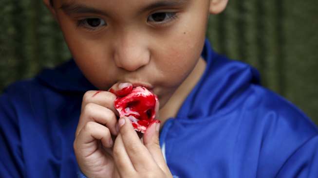 Bocah Meksiko menyantap permen berbentuk mirip hidung manusia di toko pembuat kue ala Zombie di Mexico City, Meksiko. [Reuters/Carlos Jasso]