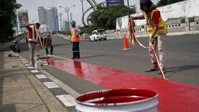 Pekerja melakukan pengecatan jalur bus Transjakarta di flyover Kuningan, Jalan HR Rasuna Said, Kuningan, Jakarta, Minggu (20/12/2015). [Suara.com/Kurniawan Mas'ud]