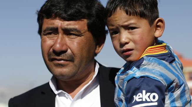 Five year-old Murtaza Ahmadi wears a shirt of Barcelona's star Lionel Messi as his father talks to the media at the Afghan Football Federation headquarters in Kabul, Afghanistan February 2, 2016.