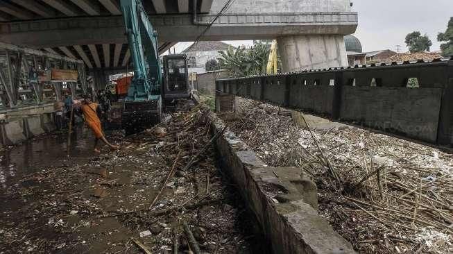 Menggunakan alat berat ekskavator, petugas membersihkan tumpukan sampah akibat hujan lebat di hulu, yang tersangkut di pondasi jembatan Jalan Kalibata Raya, Jakarta, Sabtu (5/3/2016). [Suara.com/Kurniawan Mas'ud]